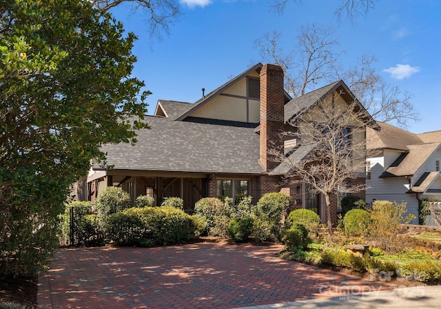 view of front of house with roof with shingles, brick siding, and a chimney