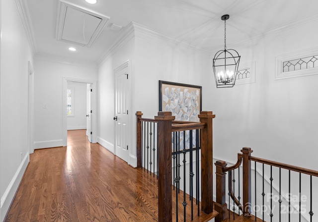 hall with attic access, crown molding, wood finished floors, and an upstairs landing