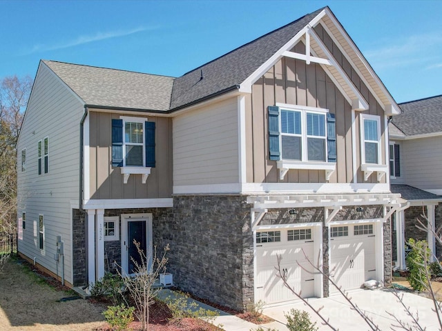 view of front facade with a garage, concrete driveway, stone siding, roof with shingles, and board and batten siding