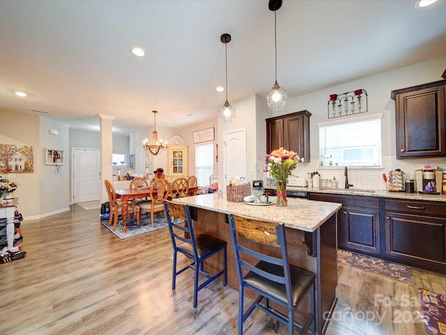 kitchen featuring a breakfast bar, light wood-type flooring, a sink, and decorative backsplash