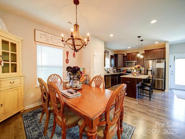 dining space featuring a notable chandelier, baseboards, wood finished floors, and recessed lighting