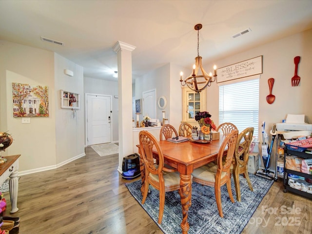 dining room with decorative columns, wood finished floors, visible vents, and baseboards