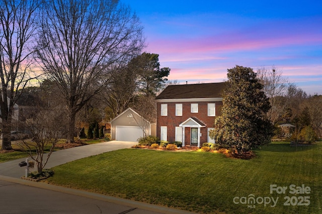 colonial inspired home featuring a garage, concrete driveway, a front lawn, and brick siding