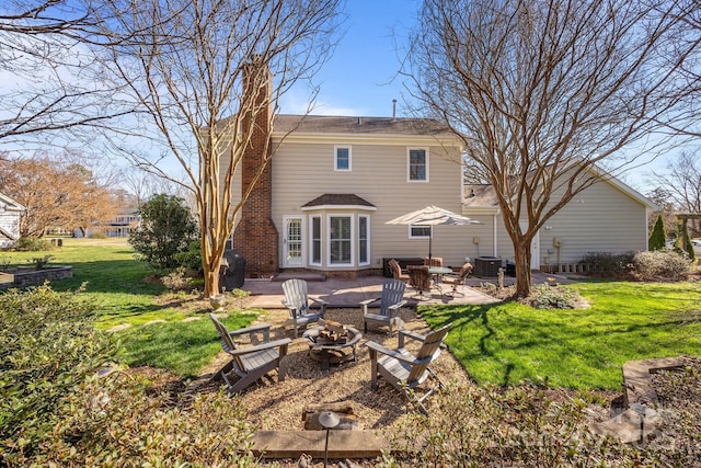 back of house featuring a fire pit, central AC, a yard, and a patio