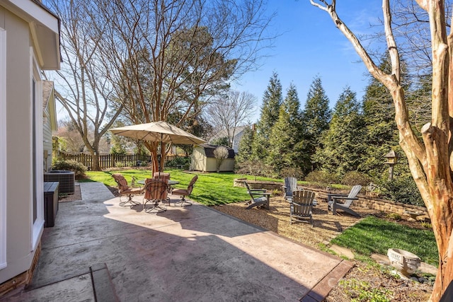 view of patio / terrace with central air condition unit, a storage unit, an outdoor fire pit, fence, and an outdoor structure