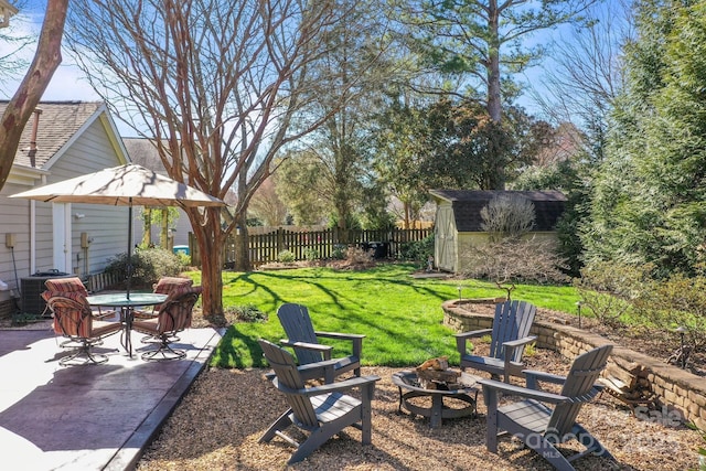 view of yard with a patio area, fence, a shed, cooling unit, and a fire pit