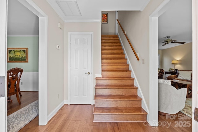 staircase featuring visible vents, ornamental molding, a ceiling fan, wood finished floors, and baseboards