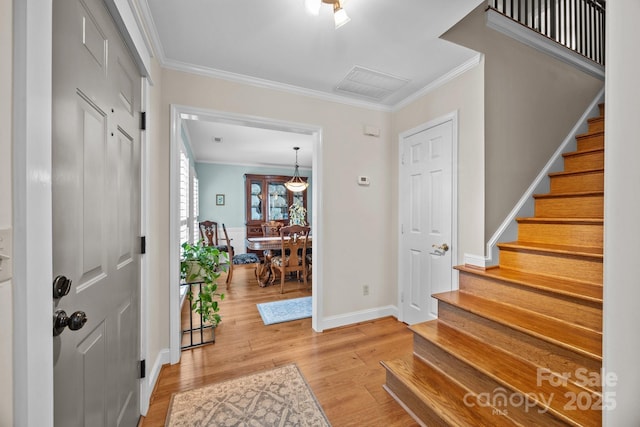 foyer entrance featuring ornamental molding, baseboards, light wood finished floors, and stairs