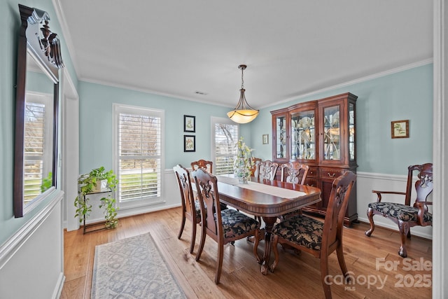 dining area with ornamental molding, light wood finished floors, and visible vents