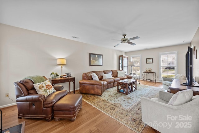 living room featuring light wood-style flooring, visible vents, ceiling fan, and baseboards