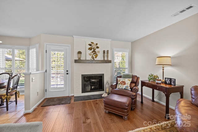 living area with a healthy amount of sunlight, visible vents, a fireplace, and wood finished floors