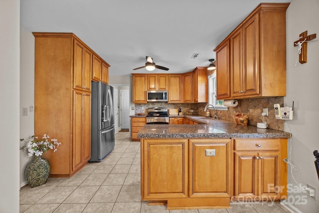 kitchen featuring appliances with stainless steel finishes, brown cabinetry, a sink, and tasteful backsplash