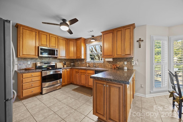 kitchen with appliances with stainless steel finishes, brown cabinetry, and backsplash