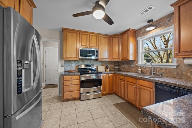 kitchen with visible vents, decorative backsplash, appliances with stainless steel finishes, brown cabinets, and a sink