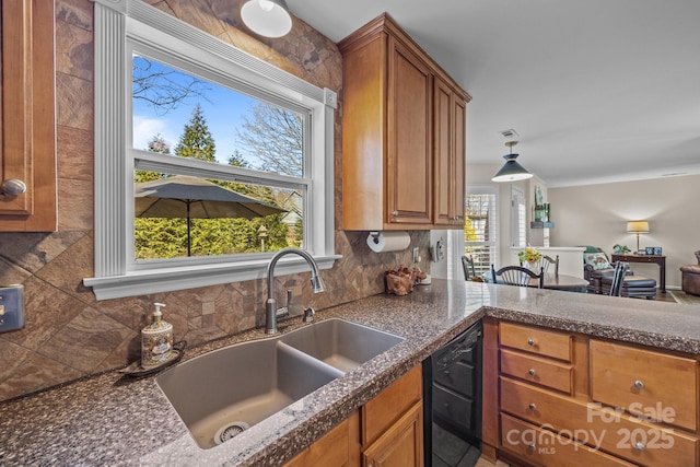 kitchen featuring dishwasher, brown cabinetry, dark countertops, and a sink