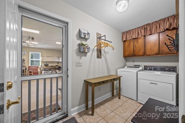 laundry area featuring washer and dryer, cabinet space, baseboards, and light tile patterned floors