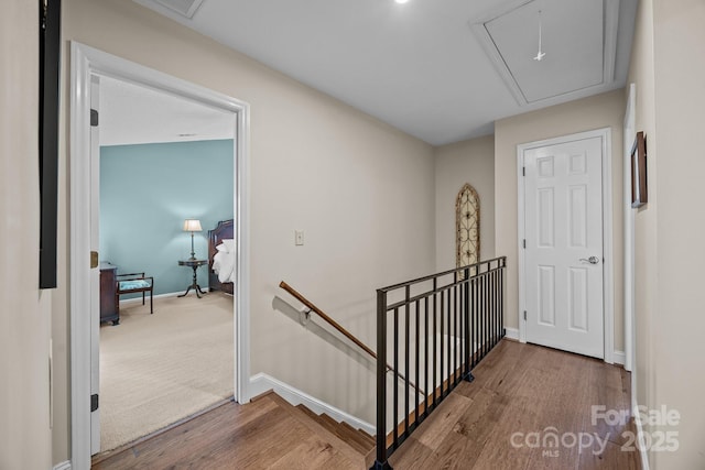 corridor with attic access, baseboards, an upstairs landing, and wood finished floors