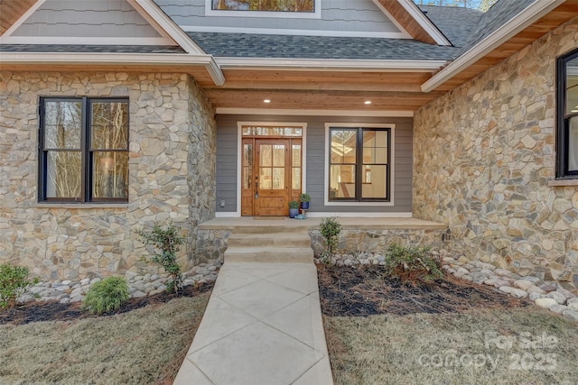 property entrance with stone siding, roof with shingles, and covered porch