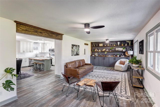 living room featuring a ceiling fan, baseboards, a dry bar, and wood finished floors