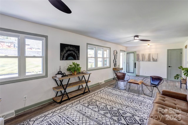 living area with ceiling fan, visible vents, and wood finished floors