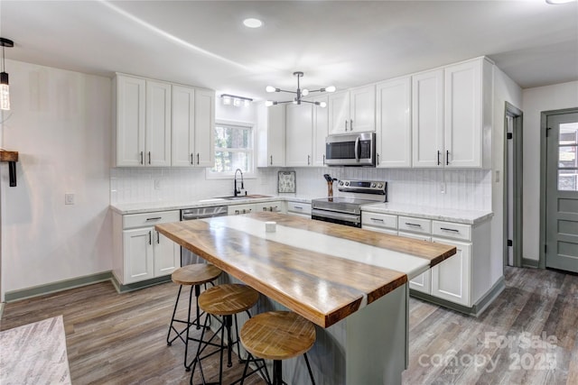 kitchen featuring stainless steel appliances, backsplash, white cabinetry, and wood counters