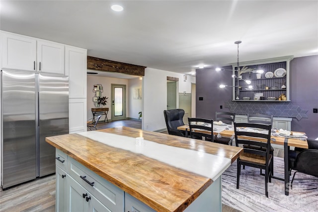 kitchen featuring tasteful backsplash, white cabinetry, butcher block countertops, light wood-type flooring, and stainless steel refrigerator