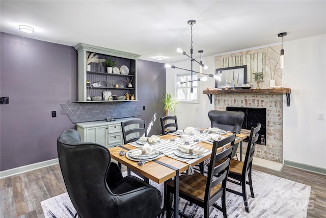 dining area with light wood-style floors, a brick fireplace, and baseboards