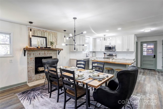 dining area featuring a brick fireplace, baseboards, a wealth of natural light, and wood finished floors