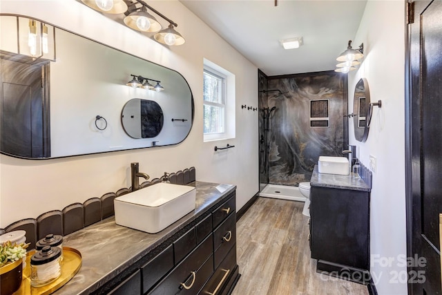 full bath with a stall shower, baseboards, toilet, wood finished floors, and vanity