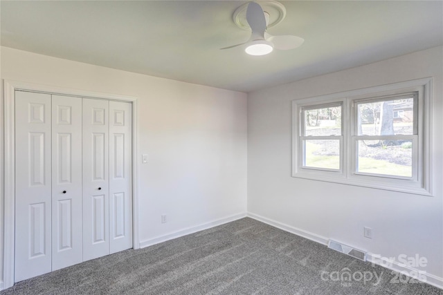 unfurnished bedroom featuring dark colored carpet, a closet, visible vents, ceiling fan, and baseboards