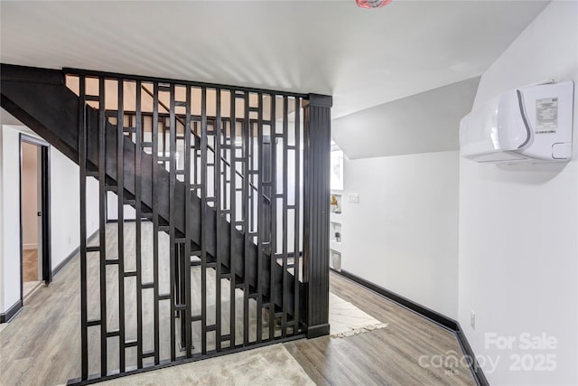 stairway with baseboards, vaulted ceiling, and wood finished floors