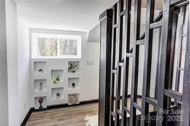 interior space with baseboards, built in features, and wood finished floors