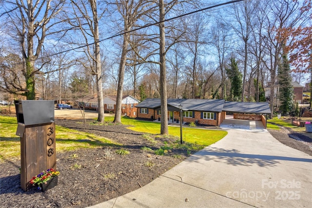 view of front of house with driveway, brick siding, an attached carport, and a front yard