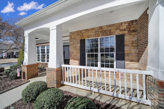 entrance to property with a porch and brick siding