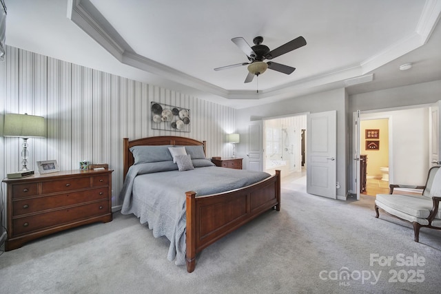 bedroom featuring light carpet, a tray ceiling, connected bathroom, and ornamental molding