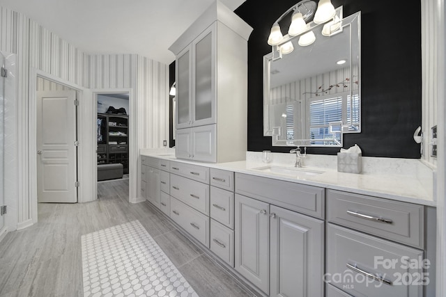 full bath featuring a spacious closet, vanity, an inviting chandelier, and walk in shower