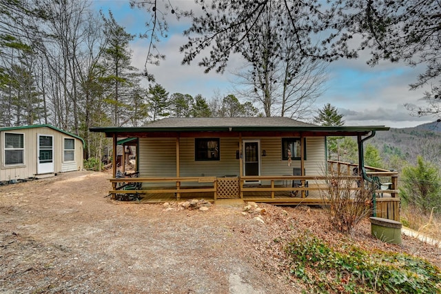 chalet / cabin featuring dirt driveway and a porch