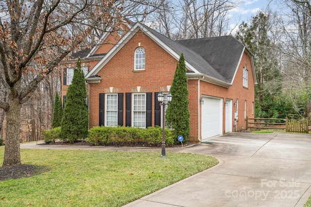 traditional home with a garage, concrete driveway, fence, a front lawn, and brick siding