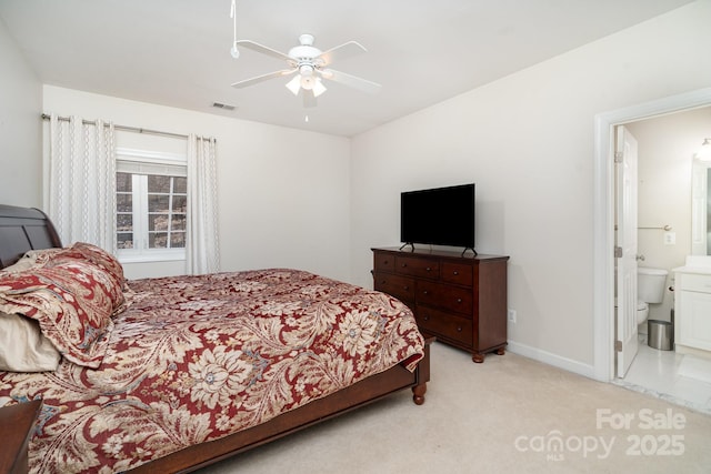 bedroom with ceiling fan, light carpet, visible vents, baseboards, and ensuite bath