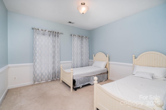 bedroom with visible vents, light carpet, and baseboards