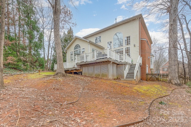 back of house with brick siding, fence, stairway, and a wooden deck