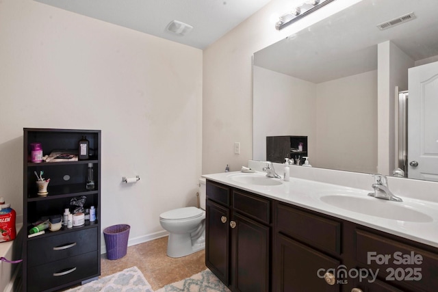 bathroom with double vanity, toilet, baseboards, and tile patterned flooring