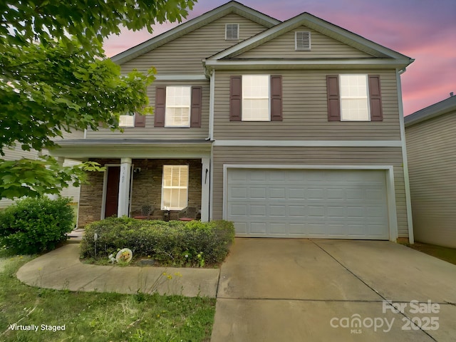 traditional-style house with an attached garage, concrete driveway, and covered porch