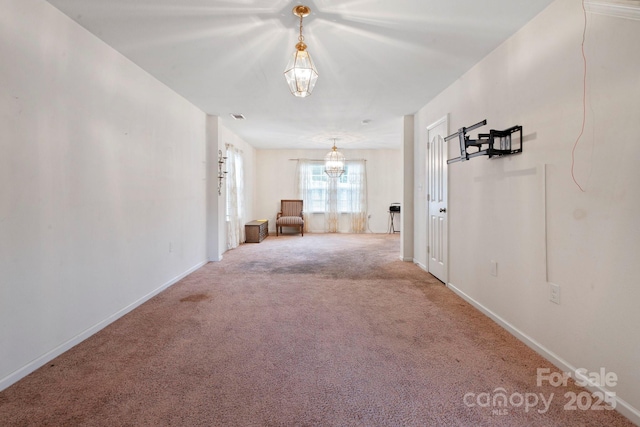 corridor featuring carpet, baseboards, and a chandelier