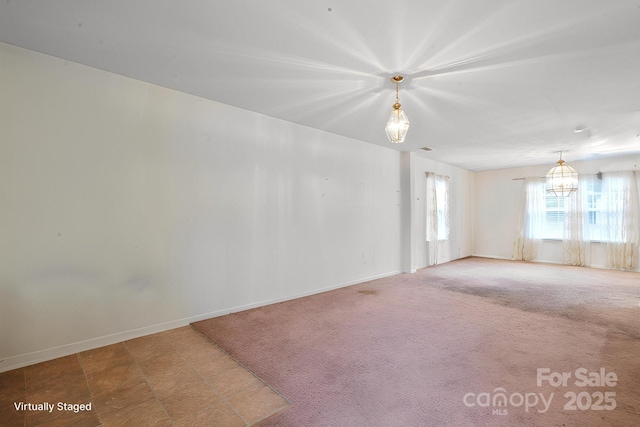 empty room featuring a chandelier and baseboards