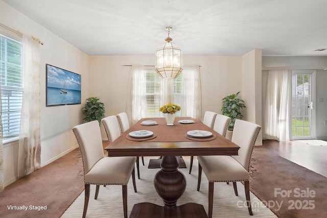 dining room featuring a chandelier, baseboards, and light colored carpet