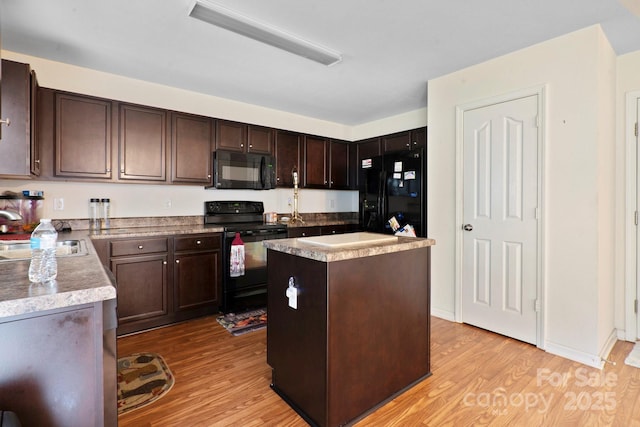 kitchen featuring black appliances, a sink, light wood-type flooring, dark brown cabinetry, and a center island