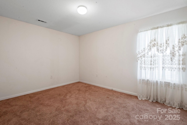 carpeted empty room featuring baseboards