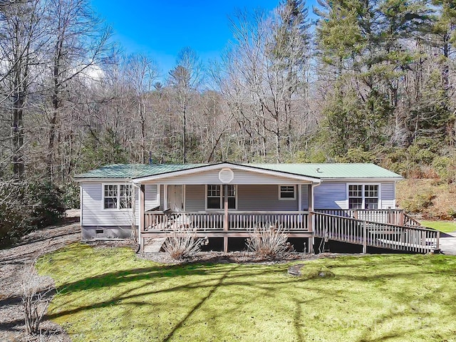 manufactured / mobile home featuring a wooded view, crawl space, metal roof, and a front lawn