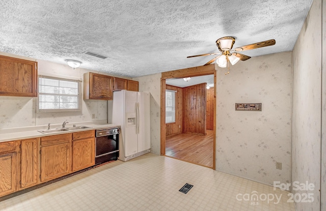 kitchen with light floors, white refrigerator with ice dispenser, dishwasher, and a sink